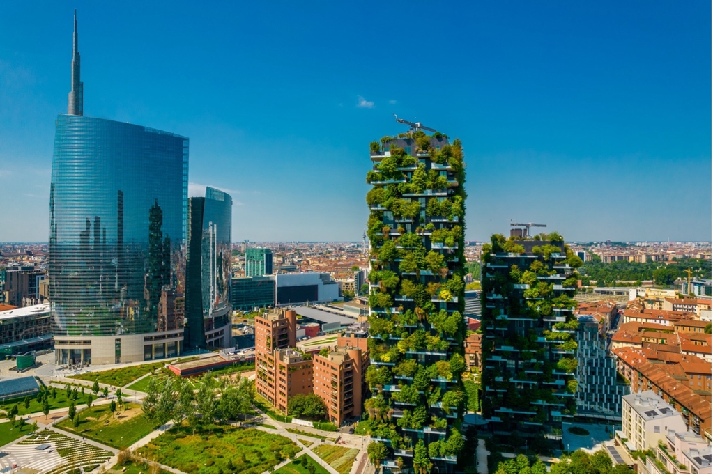 Aerial view of modern skyscrapers, including green vertical forest buildings, in a city.