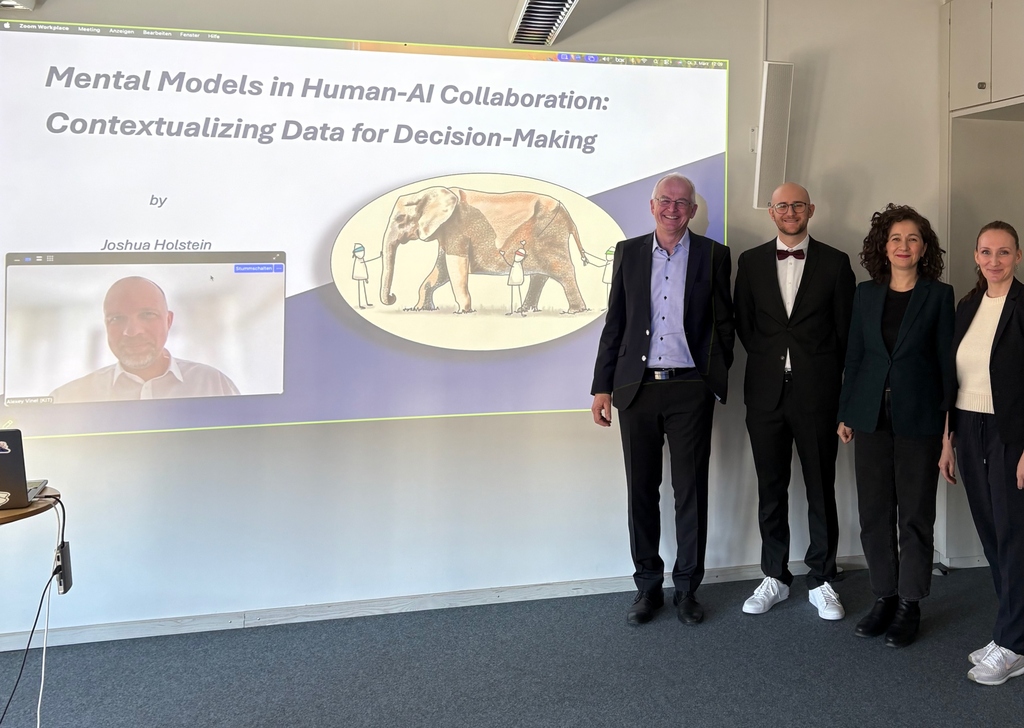 Group of people in a conference room posing for a photo while a presentation slide about "Mental Models in Human-AI Collaboration" is projected on the wall.